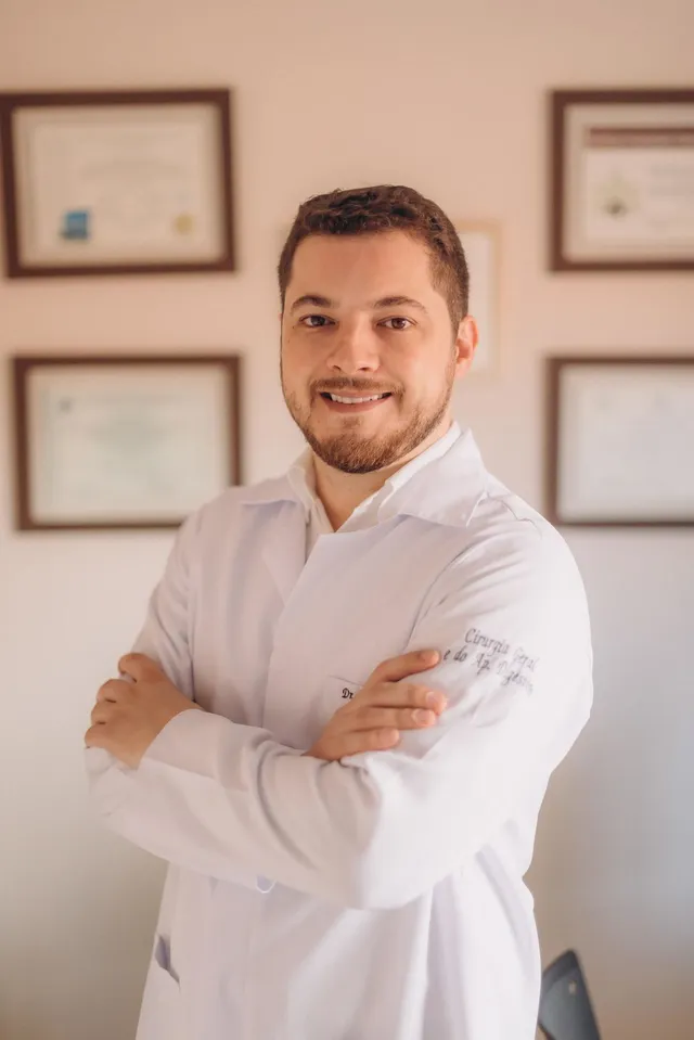Dr. Cassius Frigulha de jaleco, braços cruzados, no consultório
